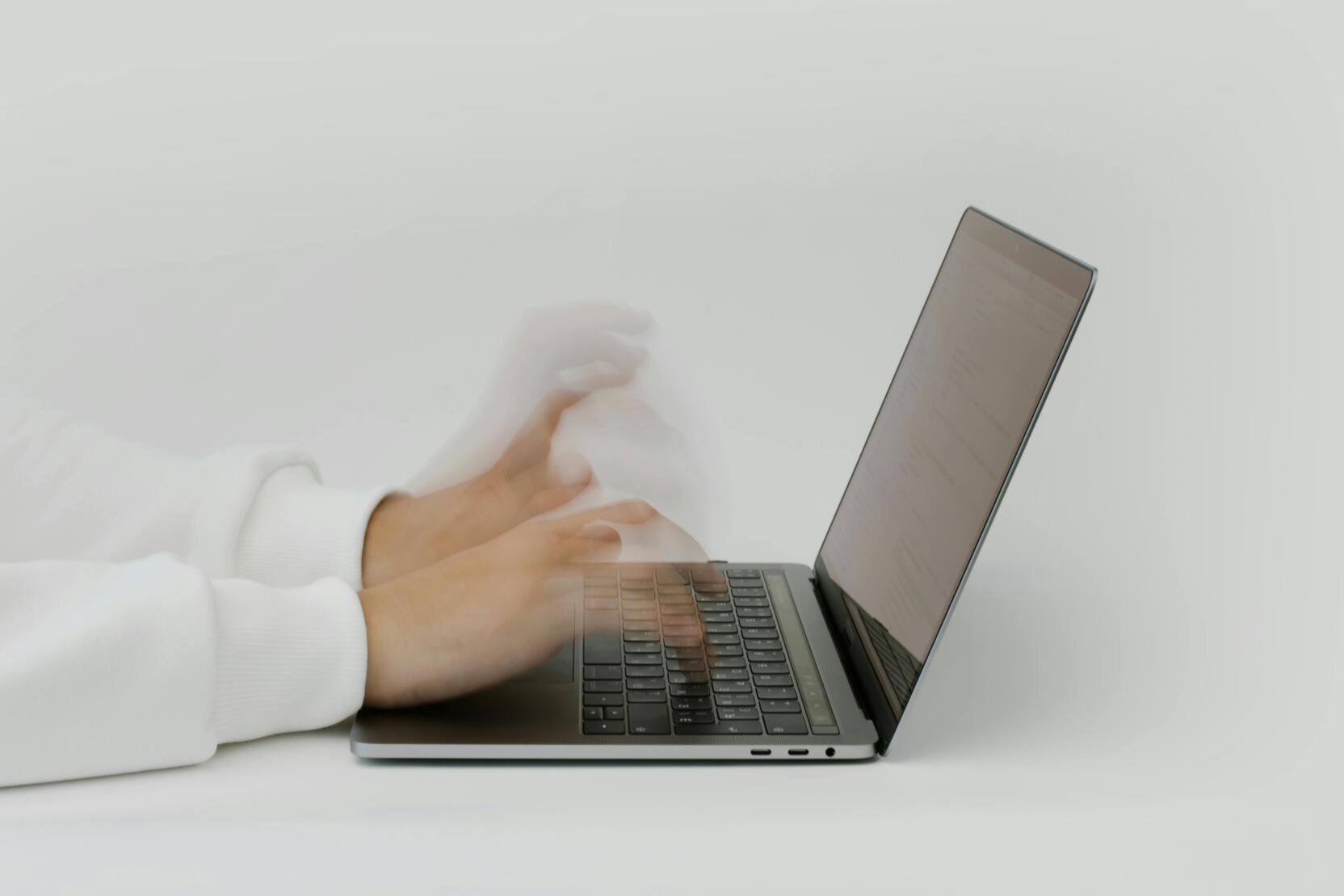 Bewegte Hände tippen schnell auf der Tastatur eines laptops vor hellem Hintergrund.